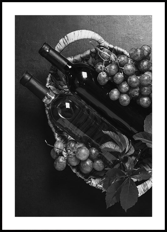 a black and white photo of a basket of grapes and a bottle of wine