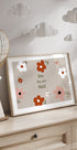 A framed print with a floral design and the text "Baby You are Magic" is displayed on a wooden dresser, with a decorative paper lantern hanging above it.