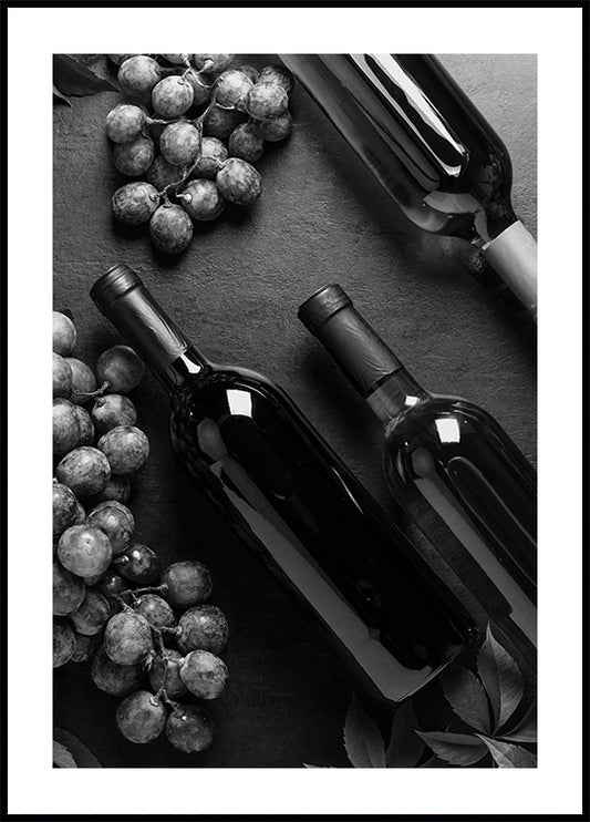 a black and white photo of wine bottles and grapes